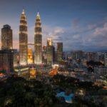 Oszałamiająca panorama Kuala Lumpur z oświetlonymi wieżami Petronas Towers o zmierzchu.