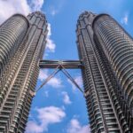 Niski kąt widzenia kultowych bliźniaczych wież Petronas w Kuala Lumpur w Malezji, na tle czystego, błękitnego nieba.