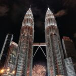 Oszałamiający widok na bliźniacze wieże Petronas oświetlone nocą zapierającym dech w piersiach pokazem sztucznych ogni w Kuala Lumpur.