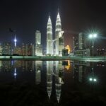 Klang: Miasto królewskie i duch historii Piękny widok na panoramę Kuala Lumpur z kultowymi wieżami Petronas Towers nocą ze światłami miasta i odbiciami.
