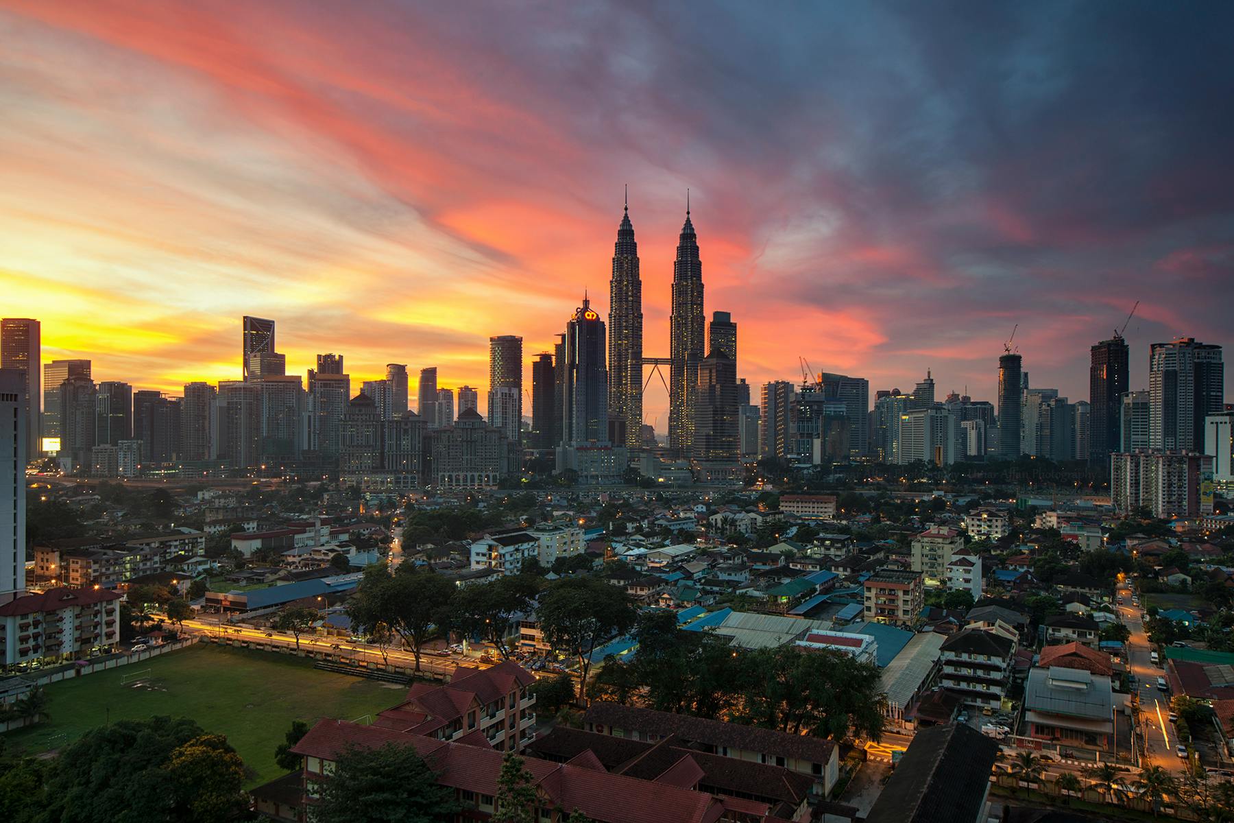 Zapierający dech w piersiach widok na panoramę Kuala Lumpur z wieżami Petronas Towers o zachodzie słońca, ukazujący tętniącą życiem architekturę miejską.