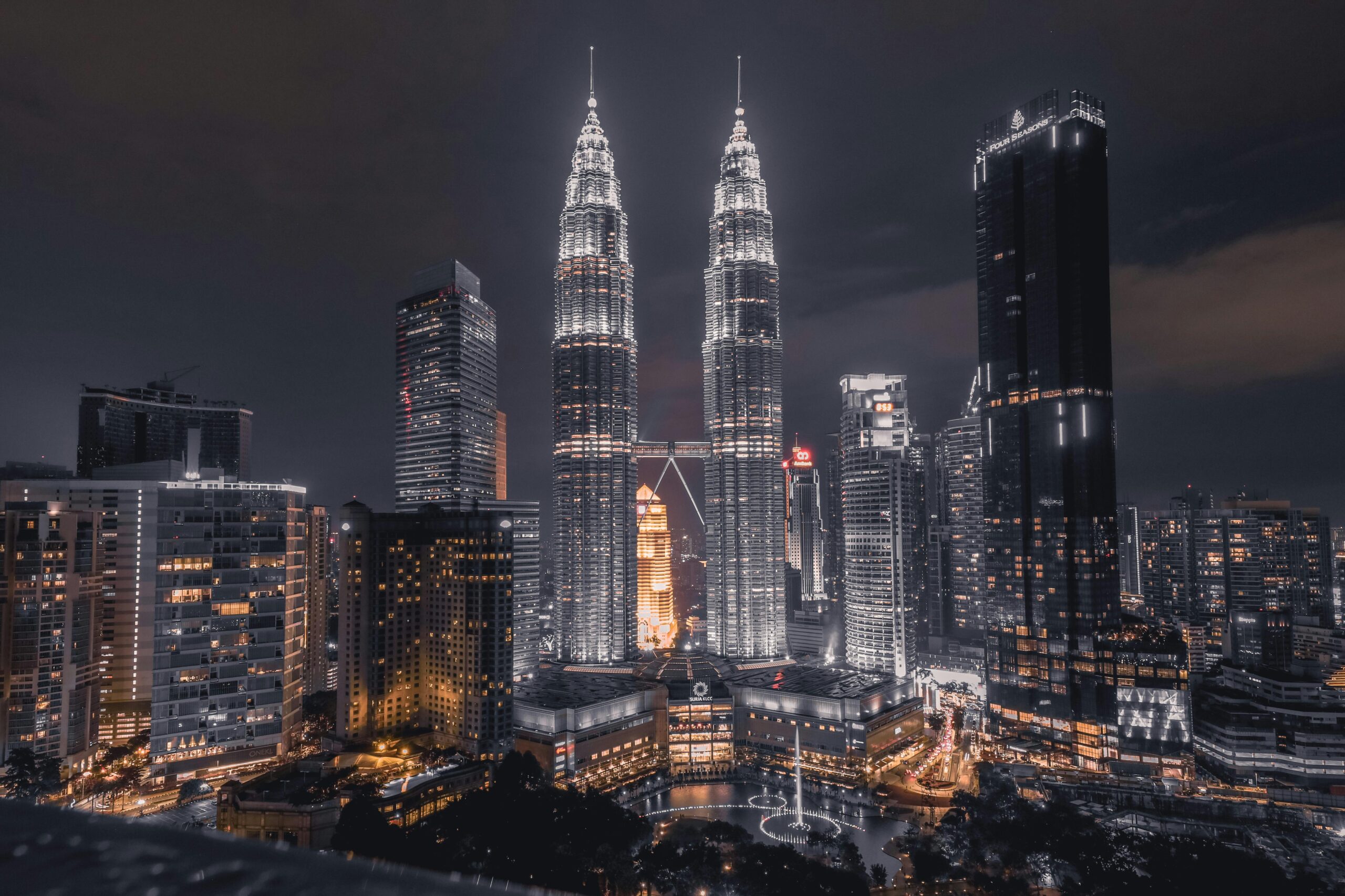 Zapierający dech w piersiach nocny widok na panoramę Kuala Lumpur z oświetlonymi wieżami Petronas Towers.