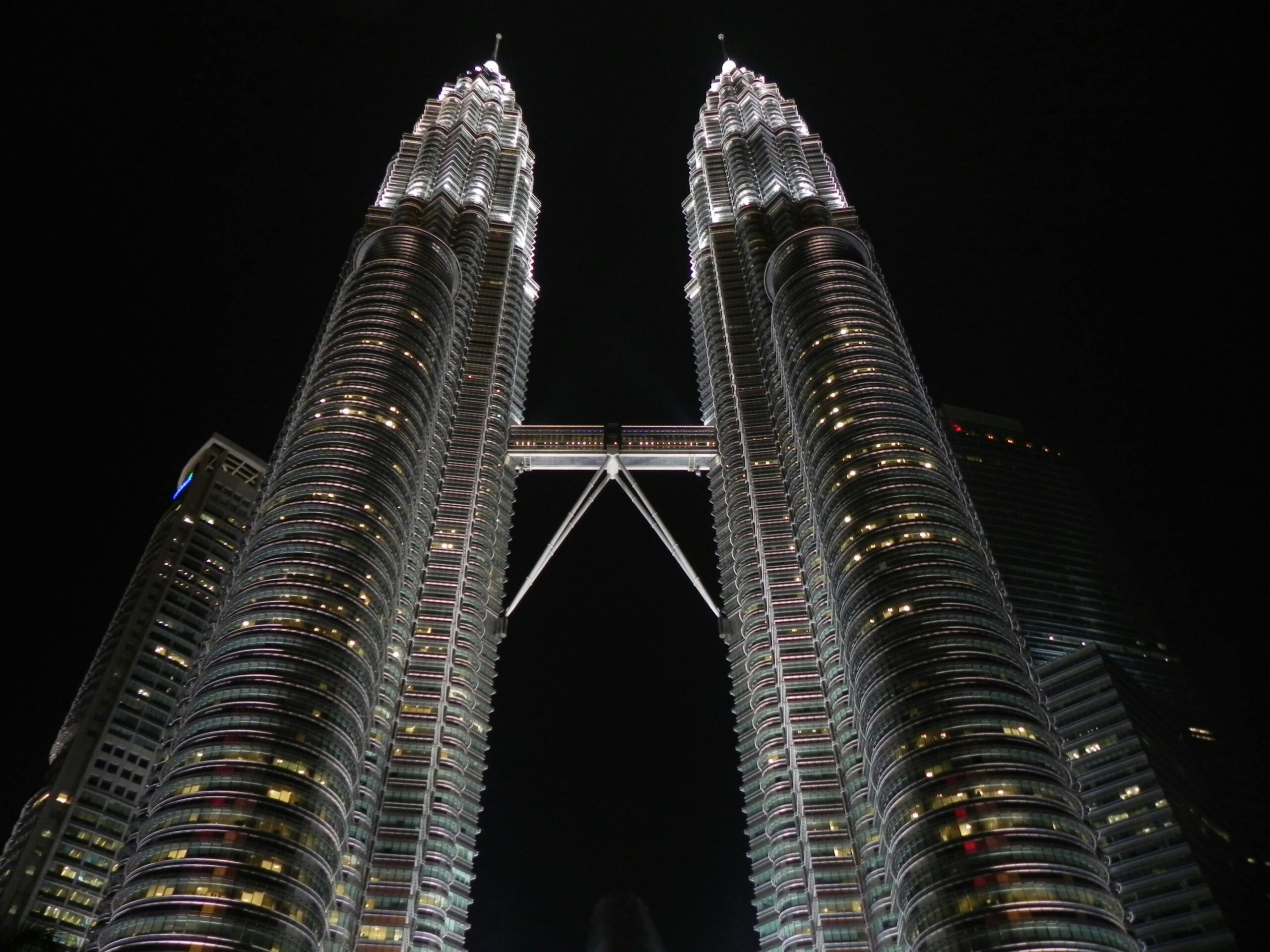 Zapierające dech w piersiach zdjęcie z niskiego kąta oświetlonych nocą Petronas Towers w Kuala Lumpur.