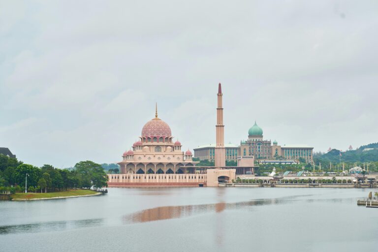 Urzekający widok na meczet Putra nad jeziorem w Putrajaya w Malezji, otoczony bujną zielenią.