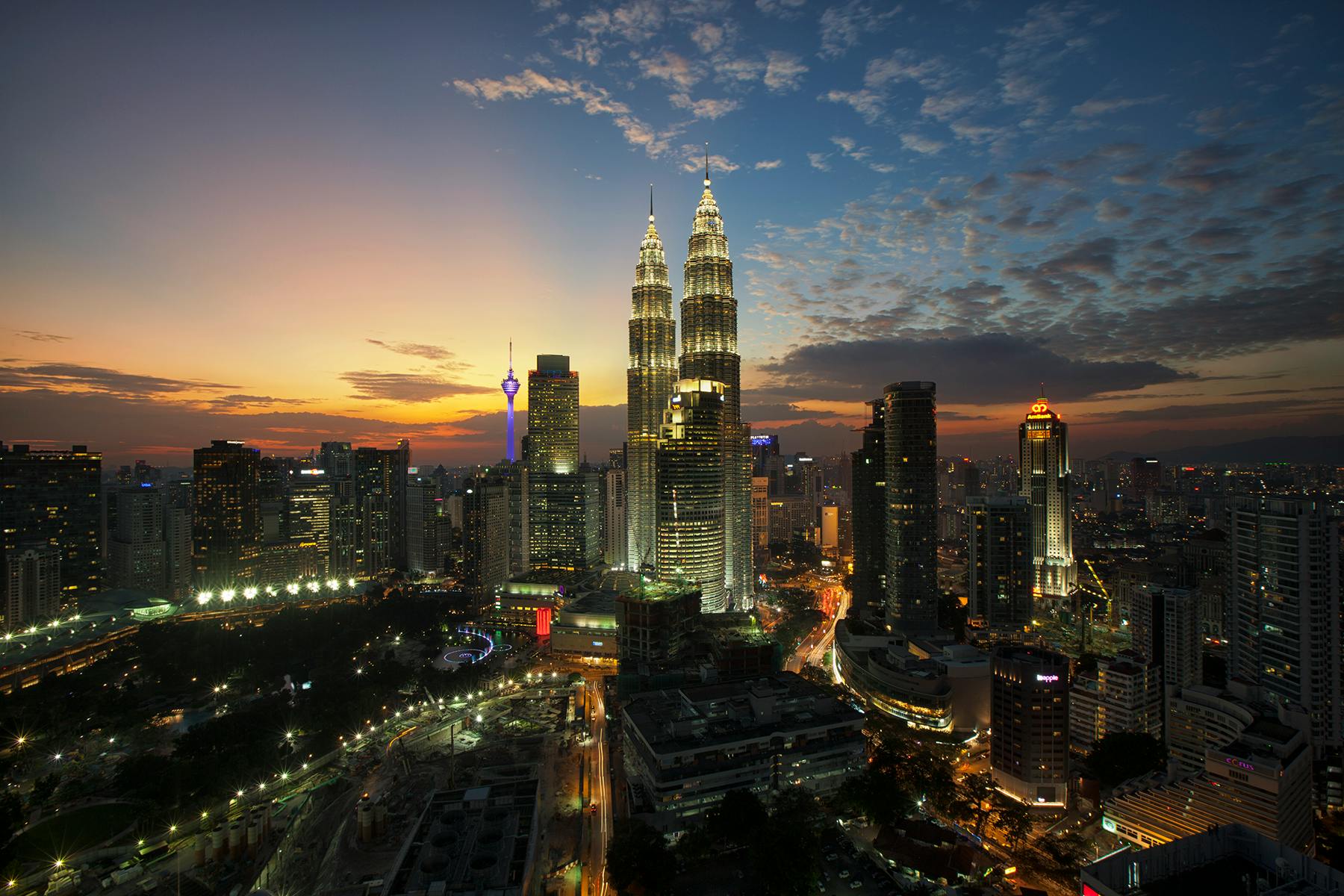Odkryj słynną panoramę Kuala Lumpur z wieżami Petronas Towers o zmierzchu, ukazującymi tętniące życiem światła miasta.