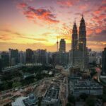 Zapierający dech w piersiach widok na panoramę Kuala Lumpur z bliźniaczymi wieżami Petronas Twin Towers o zachodzie słońca.