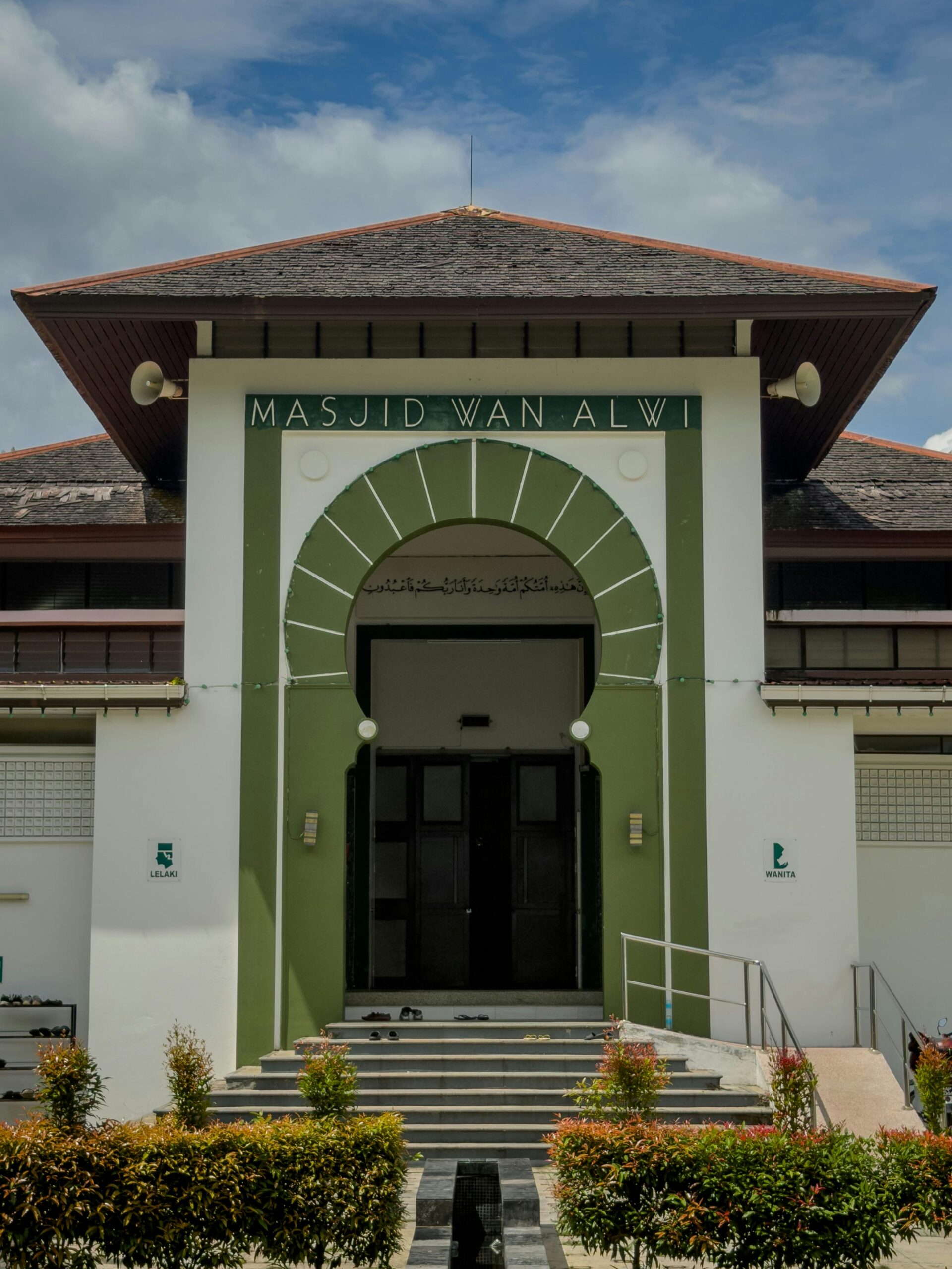 Widok z przodu Masjid Wan Alwi przedstawiający klasyczny islamski projekt architektoniczny pod czystym, błękitnym niebem.