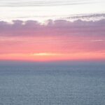 Żywy zachód słońca nad oceanem w Tangerze w Maroku, z różowymi i fioletowymi odcieniami.