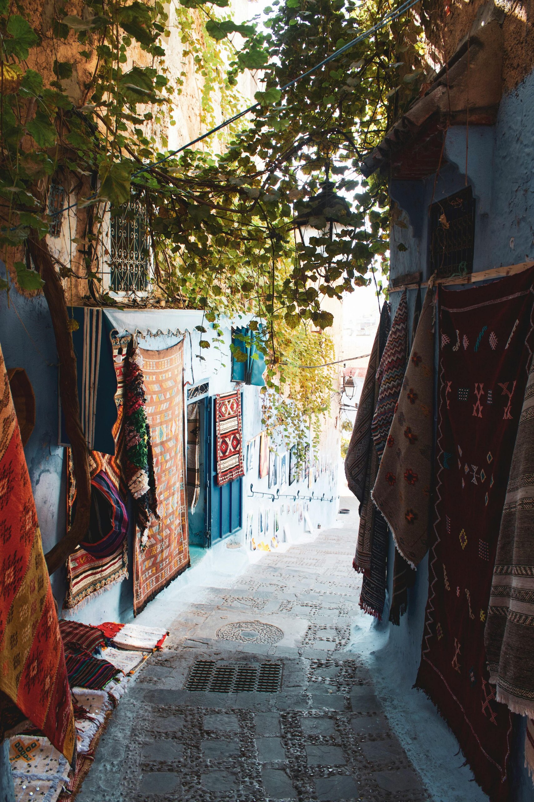 Malownicza wąska uliczka z żywymi dywanami w niebieskim mieście Chefchaouen w Maroku.