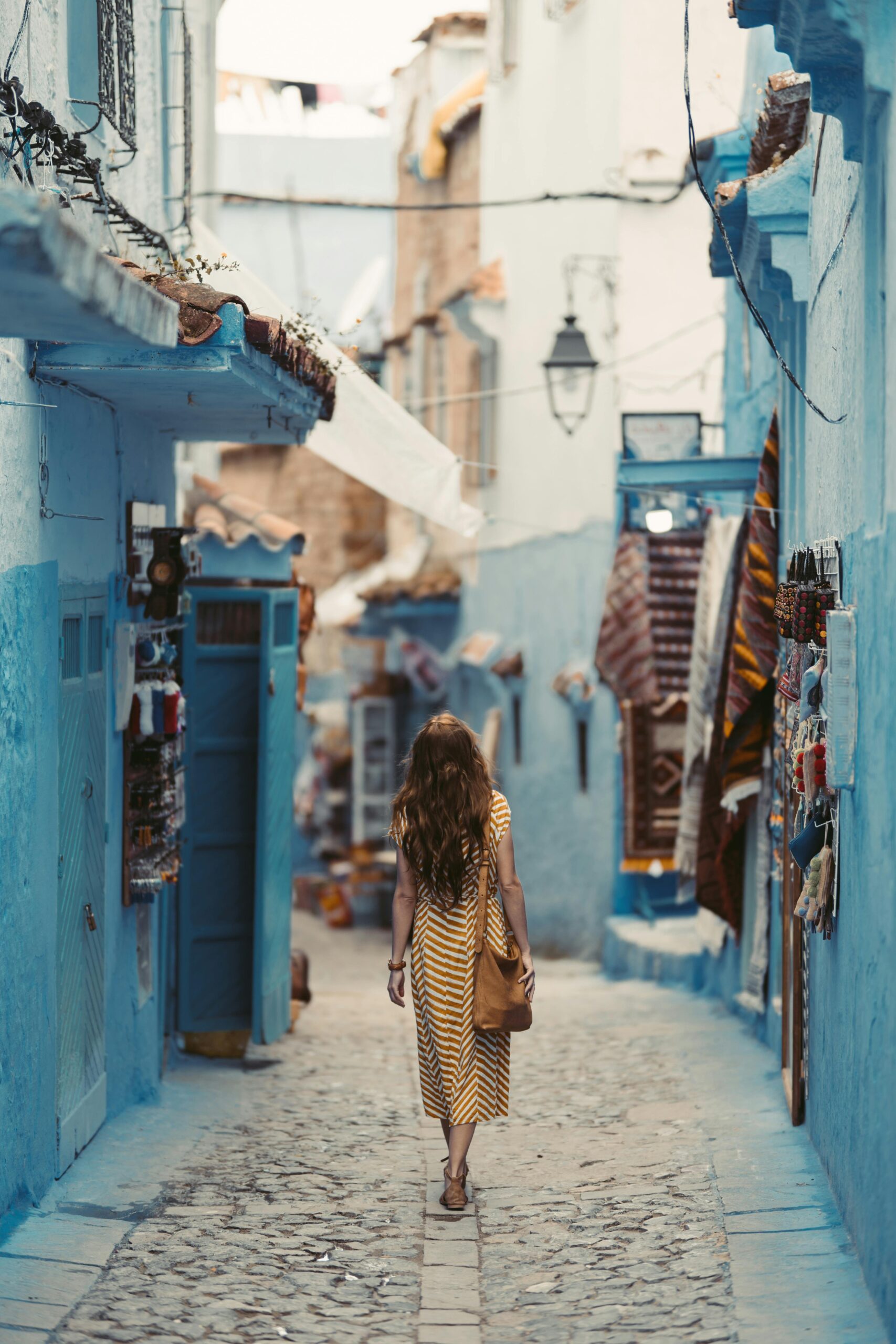 Kobieta wędruje tętniącymi życiem niebieskimi uliczkami Chefchaouen w Maroku.