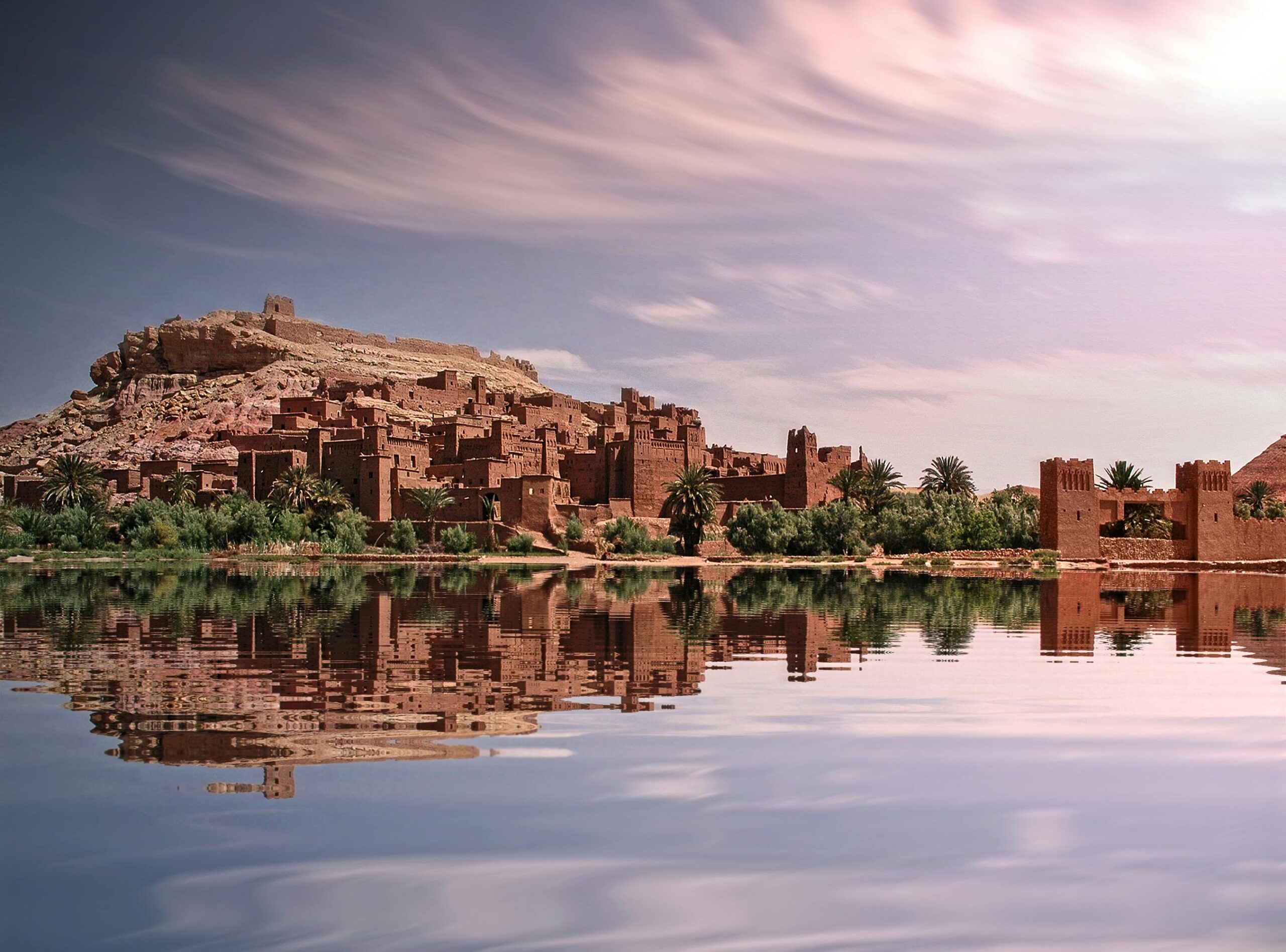 Malownicze odbicie historycznego ksara w Ouarzazate nad rzeką pod tętniącym życiem niebem.
