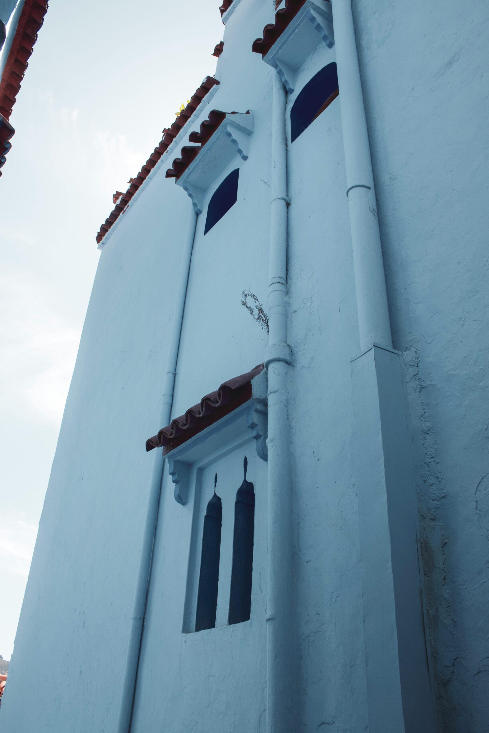 Widok pod niskim kątem na tradycyjny niebiesko-biały budynek w Chefchaouen w Maroku.