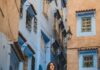 Kobieta pozuje w kultowych niebieskich uliczkach Chefchaouen w Maroku.