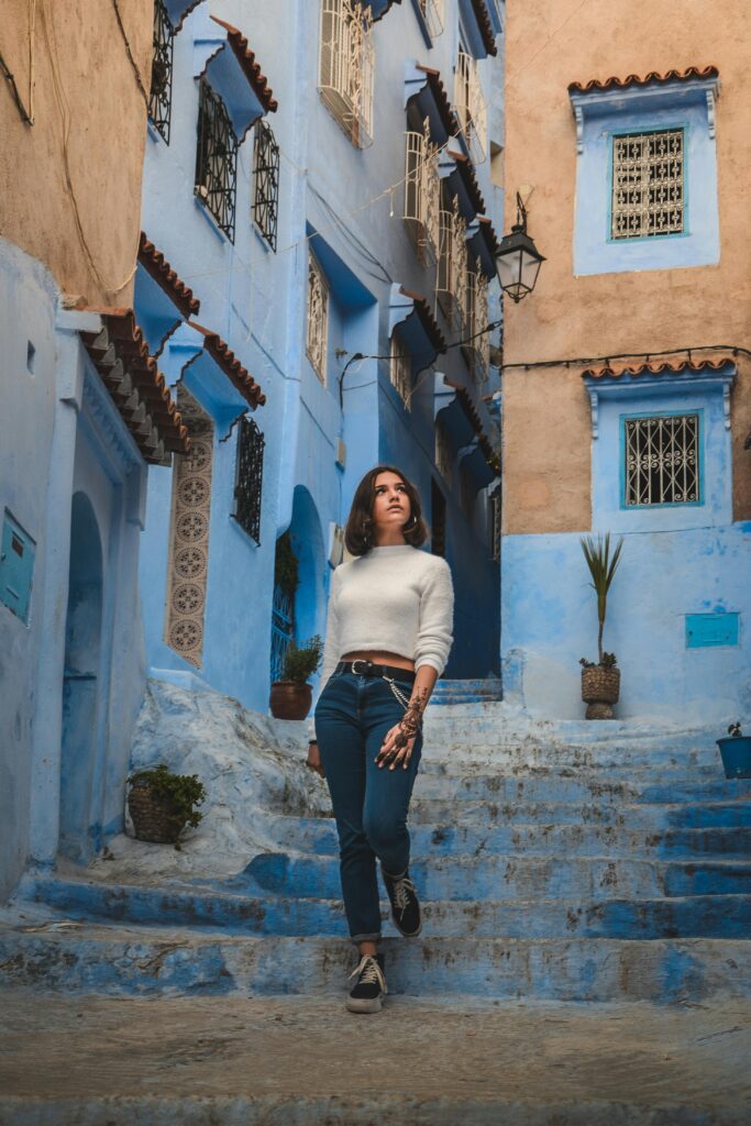 Kobieta pozuje w kultowych niebieskich uliczkach Chefchaouen w Maroku.