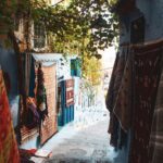 Malownicza wąska uliczka z żywymi dywanami w niebieskim mieście Chefchaouen w Maroku.