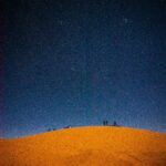 Sylwetka pustynna scena pod rozległym gwiaździstym niebem na Saharze.