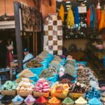 Kolorowe przyprawy i tkaniny wystawiane na targu plenerowym w Marakeszu, Maroko.