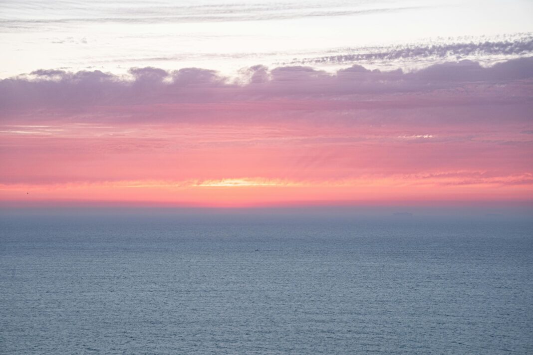 Żywy zachód słońca nad oceanem w Tangerze w Maroku, z różowymi i fioletowymi odcieniami.