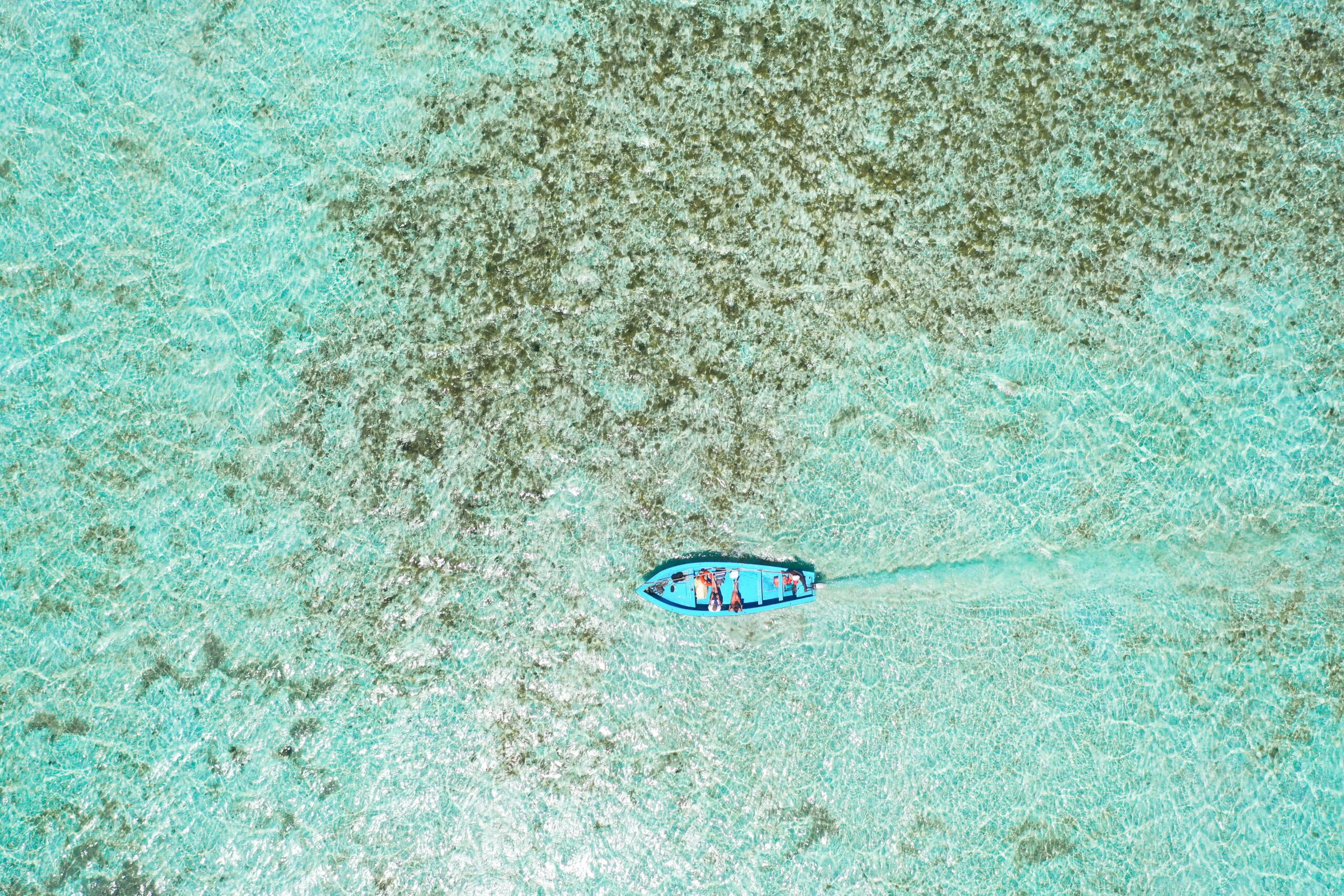 Ujęcie z drona łodzi pływającej po czystych turkusowych wodach w dystrykcie Rodrigues na Mauritiusie.