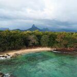 Mauritius – rejsy wokół wyspy i sąsiednich atolów Oszałamiający widok z lotu ptaka na plażę w dystrykcie Rivière Noire na Mauritiusie, na tle bujnych drzew i gór.