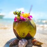 Wibrujący napój kokosowy z kwiatami na piaszczystej plaży na Mauritiusie, idealny do motywów tropikalnych.