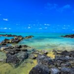 Najpiękniejsze plaże Mauritiusa – TOP 10 Piękna scena przybrzeżna na Mauritiusie z czystymi turkusowymi wodami i skalistymi brzegami.