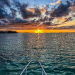 Oszałamiający zachód słońca nad spokojnymi wodami w Cap Malheureux na Mauritiusie z łodzią na pierwszym planie.