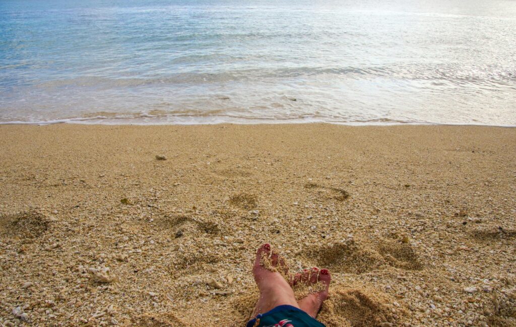 Stopy na piaszczystej plaży z delikatnymi falami na Mauritiusie w dzielnicy Plaines Wilhems.