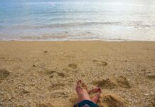 Stopy na piaszczystej plaży z delikatnymi falami na Mauritiusie w dzielnicy Plaines Wilhems.