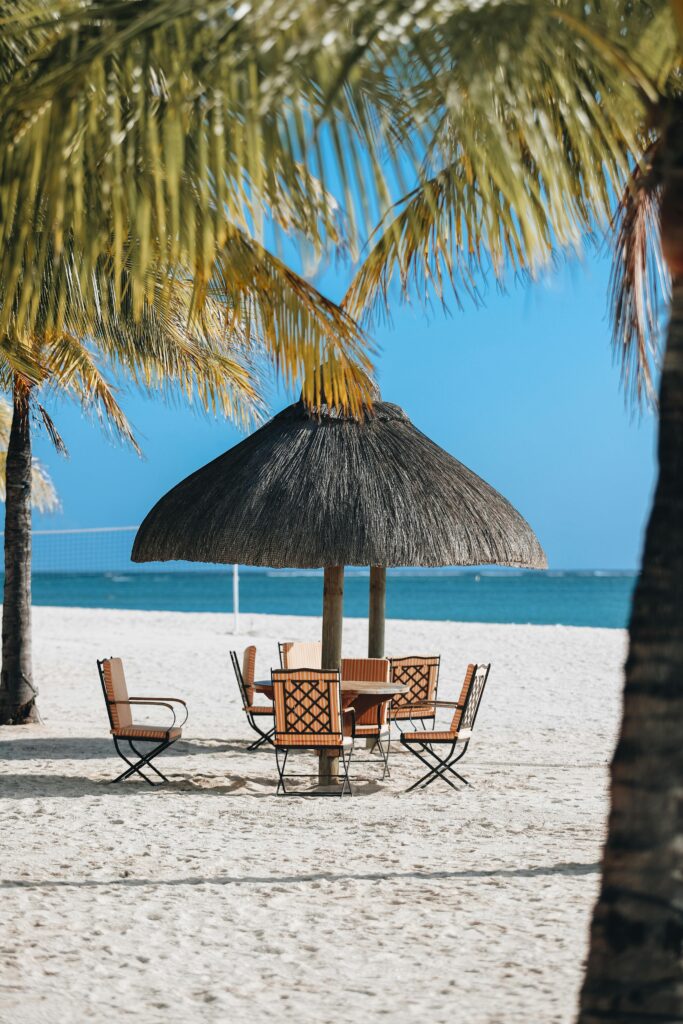 Spokojna plaża pod palmami z krzesłami i parasolem na wybrzeżu Mauritiusa.