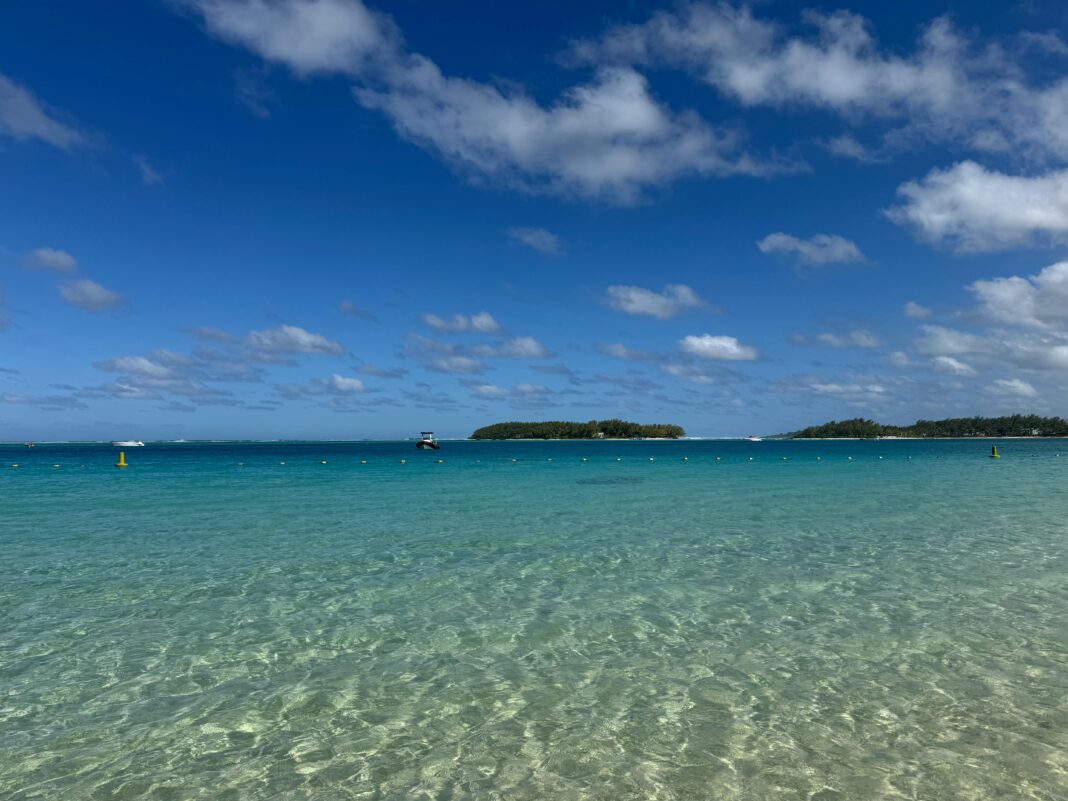 Krystalicznie czyste wody w Blue Bay, Grand Port District, Mauritius pod tętniącym życiem błękitnym niebem.