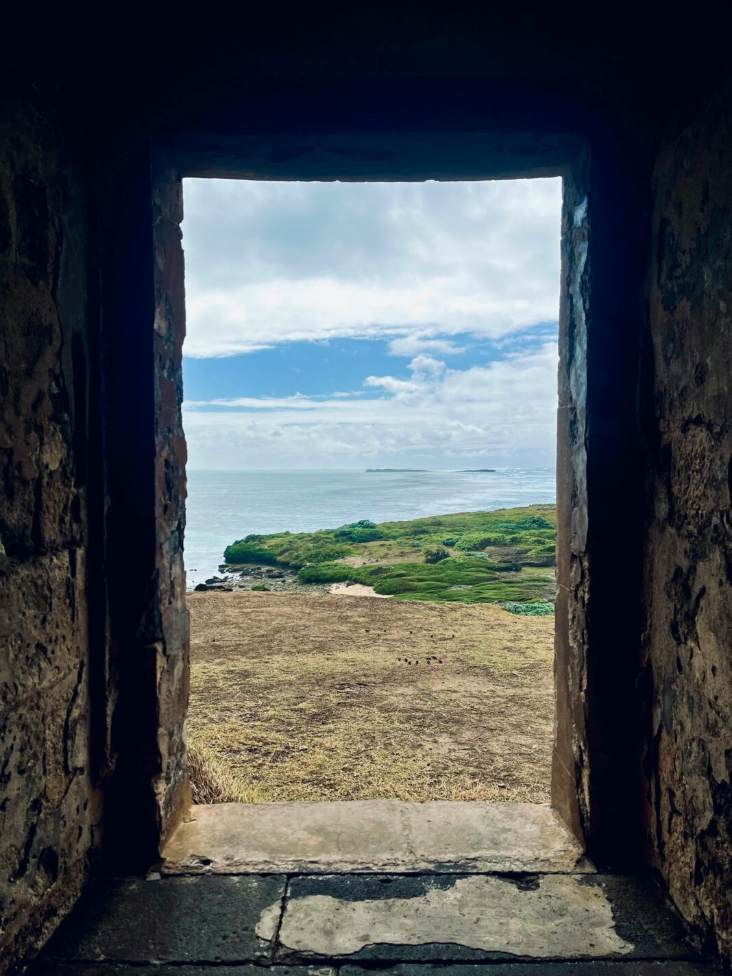 Widok na bujny krajobraz wybrzeża przez okno twierdzy na Mauritiusie.