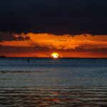 Zapierający dech w piersiach widok na pomarańczowy zachód słońca nad spokojnymi wodami Oceanu Indyjskiego.