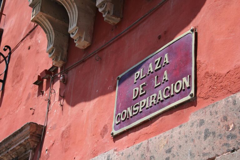 Żywa czerwona ściana ze znakiem Plaza de la Conspiración w San Miguel de Allende w Meksyku.