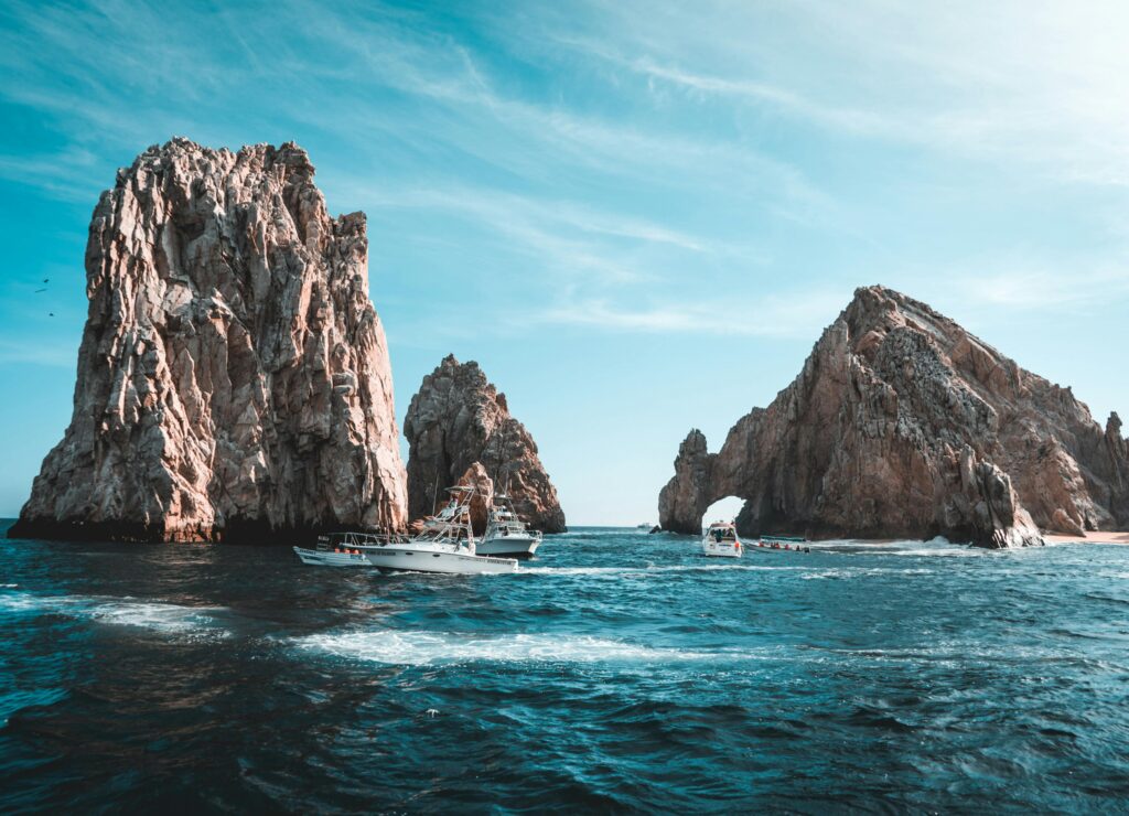 Oszałamiający krajobraz morski Cabo San Lucas z formacjami skalnymi i łodziami w pogodny dzień.