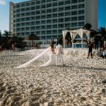 Wspaniały ślub na plaży z parą młodą na piaszczystym brzegu przed hotelem wypoczynkowym.