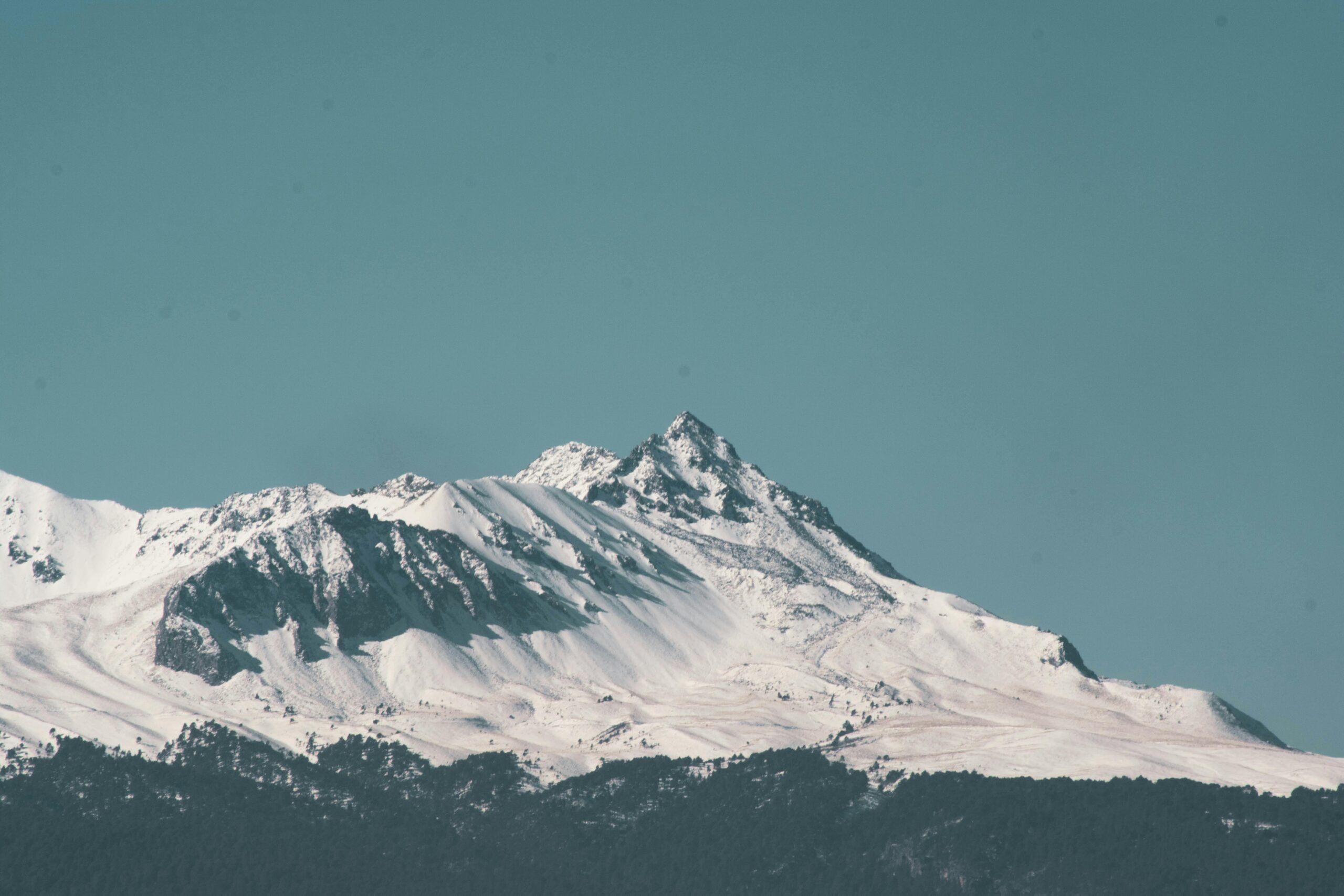 Zapierający dech w piersiach widok na ośnieżone góry pod czystym, błękitnym niebem zimą.