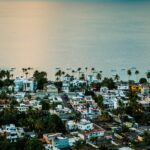 Widok z lotu ptaka na meksykańskie nadmorskie miasteczko z palmami i oceanem w świetle dziennym.