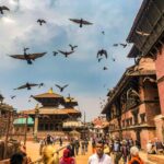 Trisuli River: Rafting wśród spektakularnych krajobrazów Wibrująca scena na placu Patan Durbar z ludźmi, gołębiami i tradycyjną architekturą Newari pod zachmurzonym niebem.