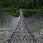 Most wiszący w bujnym nepalskim lesie oferujący ścieżkę pełną przygód.