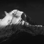 Oszałamiający czarno-biały widok na góry Annapurna z ośnieżonymi szczytami i dramatycznymi chmurami.