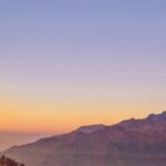 Dwóch turystów podziwia wschód słońca podczas pełni księżyca w Lwang Ghalel w Nepalu.