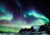 Majestatyczna zorza polarna oświetla ośnieżone wybrzeże Lenvik w Troms w Norwegii.