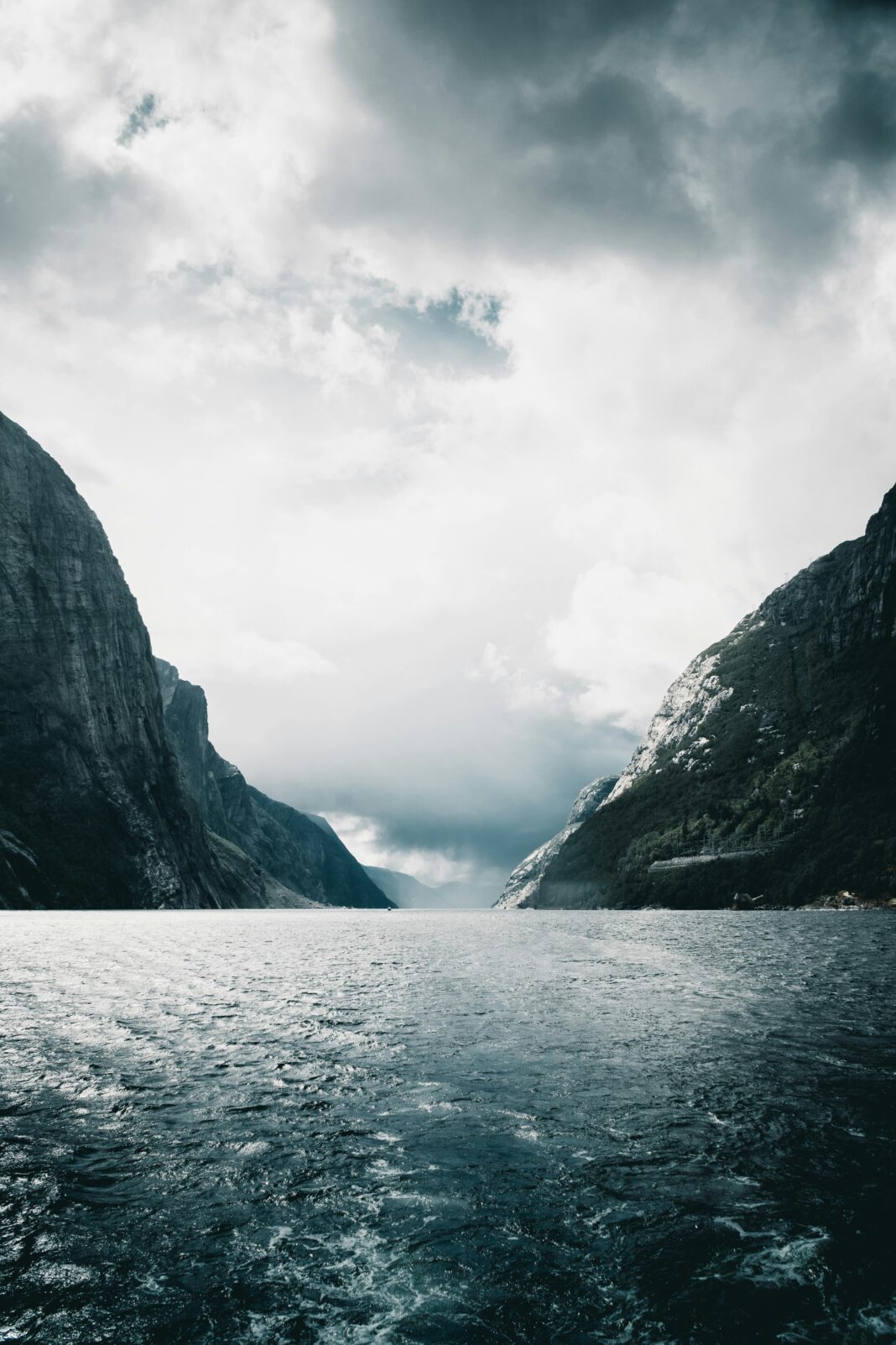 norwegia Majestatyczny widok na Lysefjord z wysokimi wapiennymi klifami i spokojną wodą pod zachmurzonym niebem.