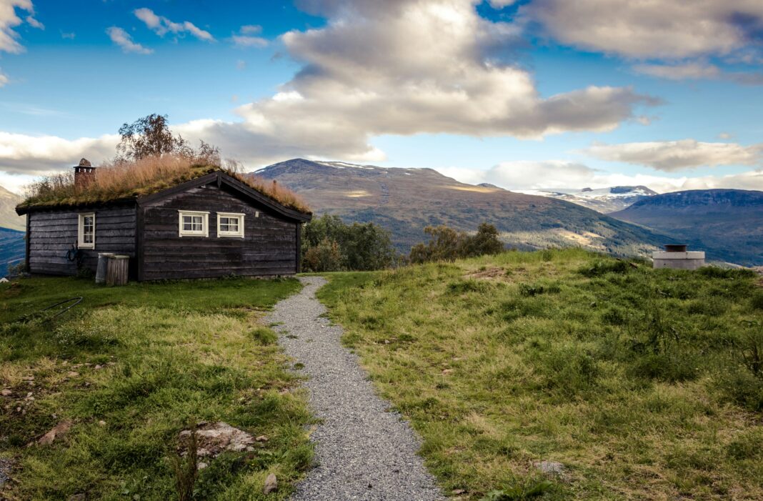 norwegia Idylliczna wiejska chata z trawiastym dachem na tle zapierającego dech w piersiach górskiego krajobrazu.