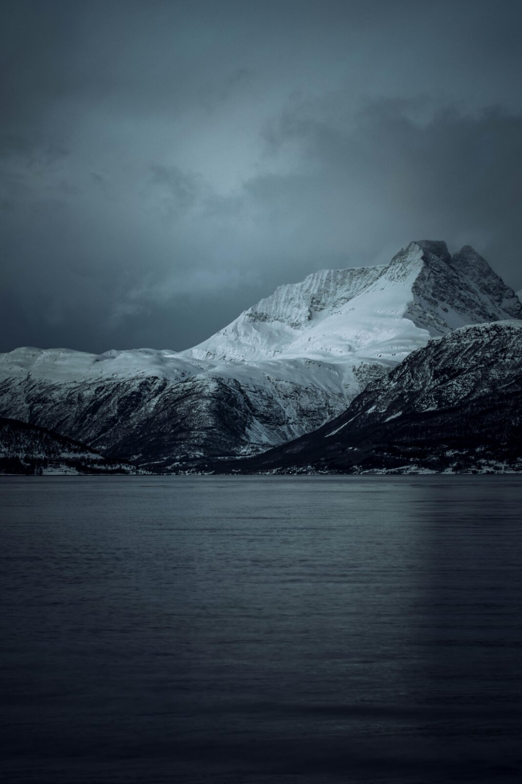 Poczuj spokojne piękno pokrytych śniegiem gór w Norwegii, uchwycone o zmierzchu.