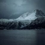 Poczuj spokojne piękno pokrytych śniegiem gór w Norwegii, uchwycone o zmierzchu.