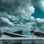 Dramatyczny widok na Operę w Oslo na tle pochmurnego nieba, z widokiem na nabrzeże.