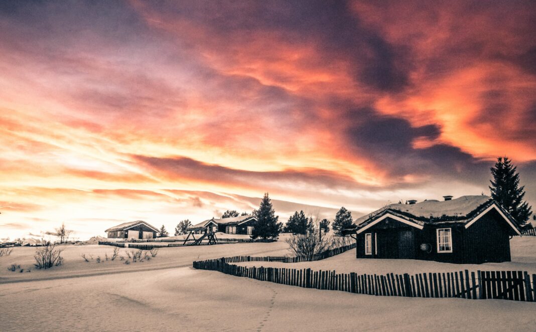 norwegia Urzekający zachód słońca nad zaśnieżoną wioską w Hol w Norwegii, ukazujący zimowe piękno.