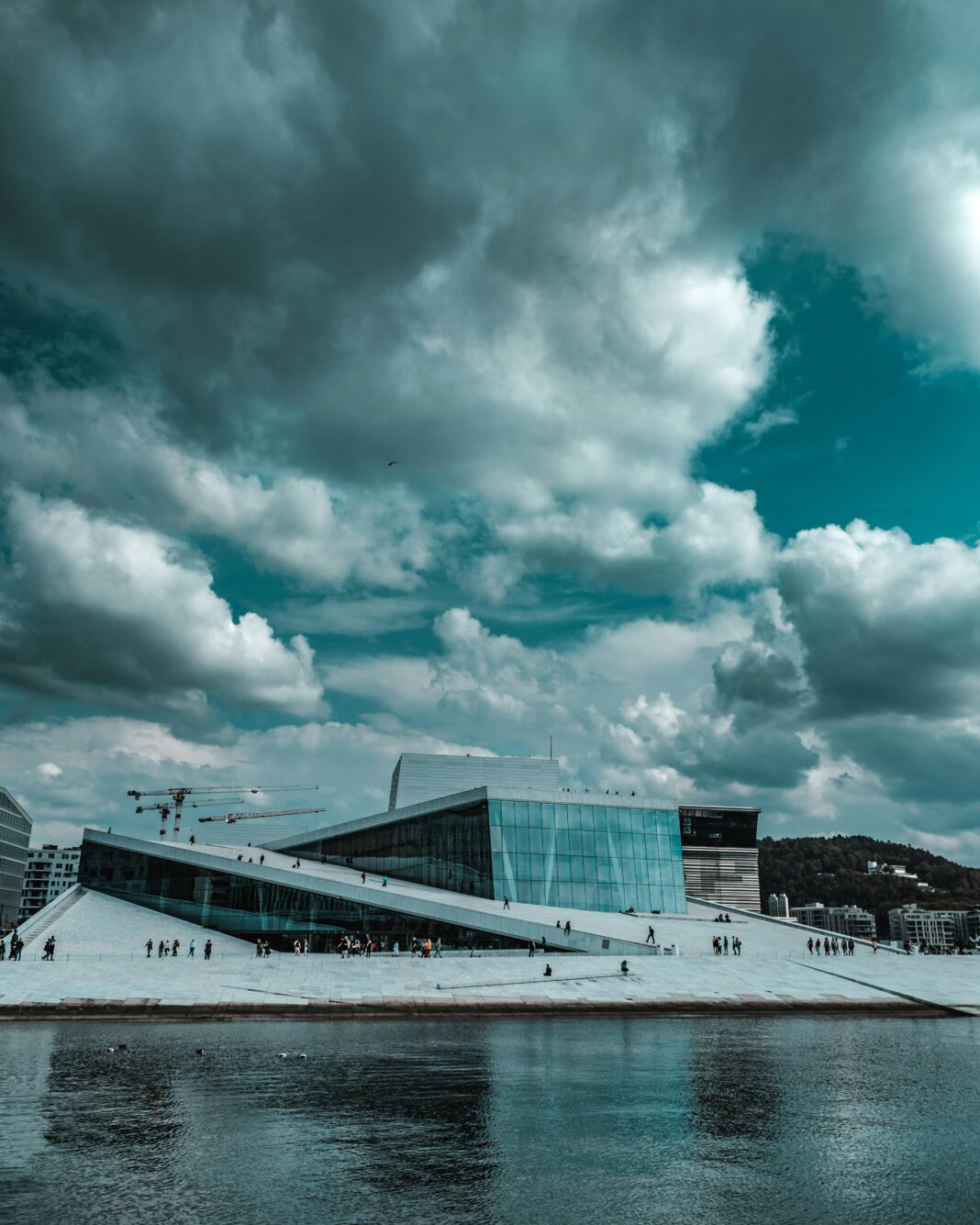 Dramatyczny widok na Operę w Oslo na tle pochmurnego nieba, z widokiem na nabrzeże.